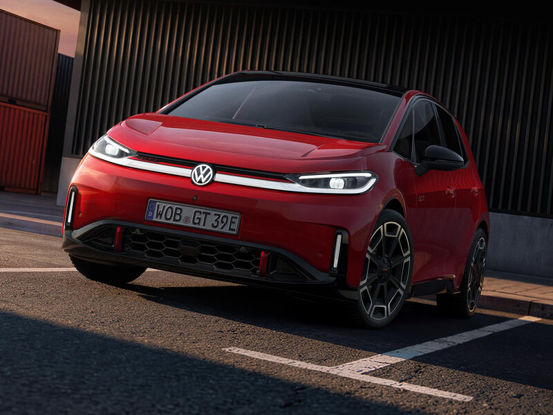 Roter Volkswagen ID.3 GTI aus der schrägen Frontperspektive auf einer Straße vor einem dunklen Gebäude mit vertikaler Lamellenfassade