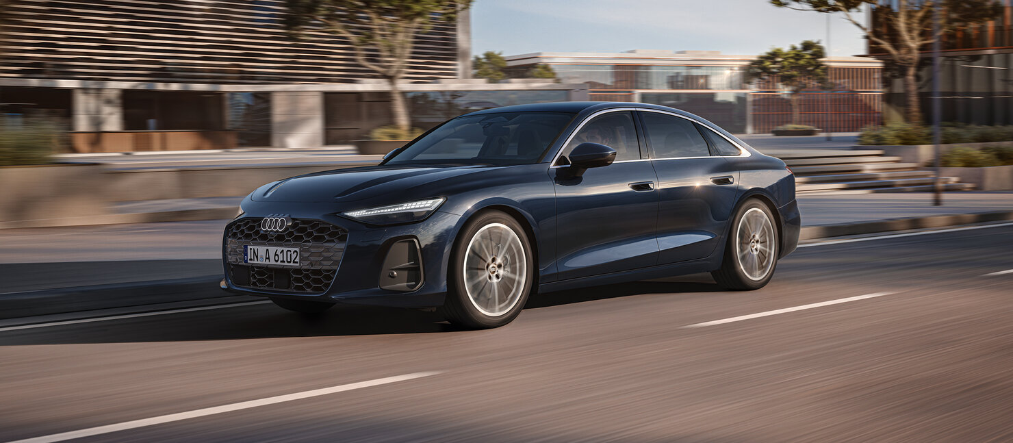 Audi A6 Limousine fährt dynamisch durch urbane Umgebung und verbindet sportliche Eleganz mit souveräner Präsenz