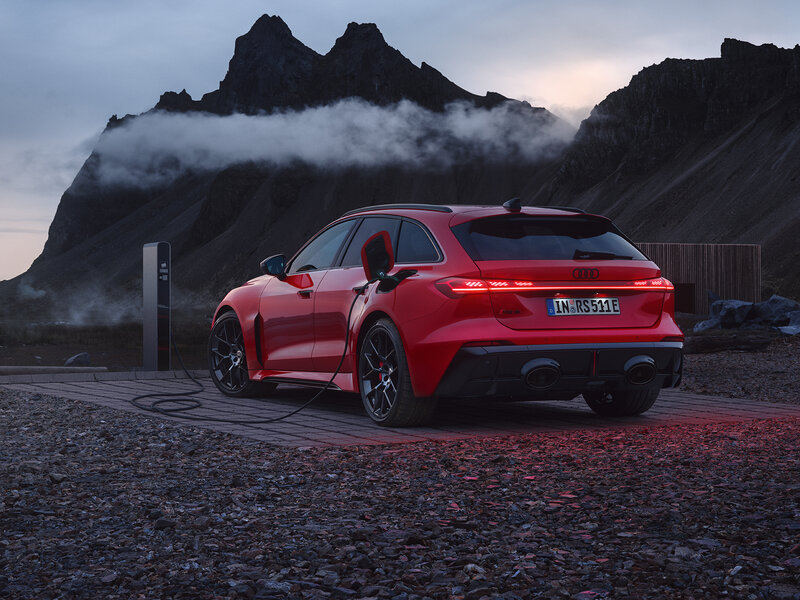 Audi RS 5 Avant in Rot aus Heckperspektive auf nasser Straße vor Berglandschaft mit tiefhängenden Wolken