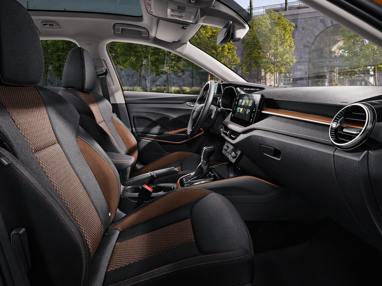 Innenraum des Škoda Fabia in Kupferorange mit zweifarbigen Vordersitzen, zentralem Display und Blick auf Armaturenbrett und Mittelkonsole.