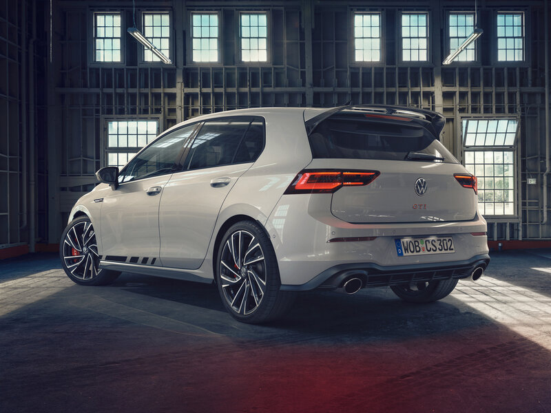 Heckansicht eines weißen Volkswagen Golf GTI in einer Industriehalle mit sportlicher Lichtstimmung.