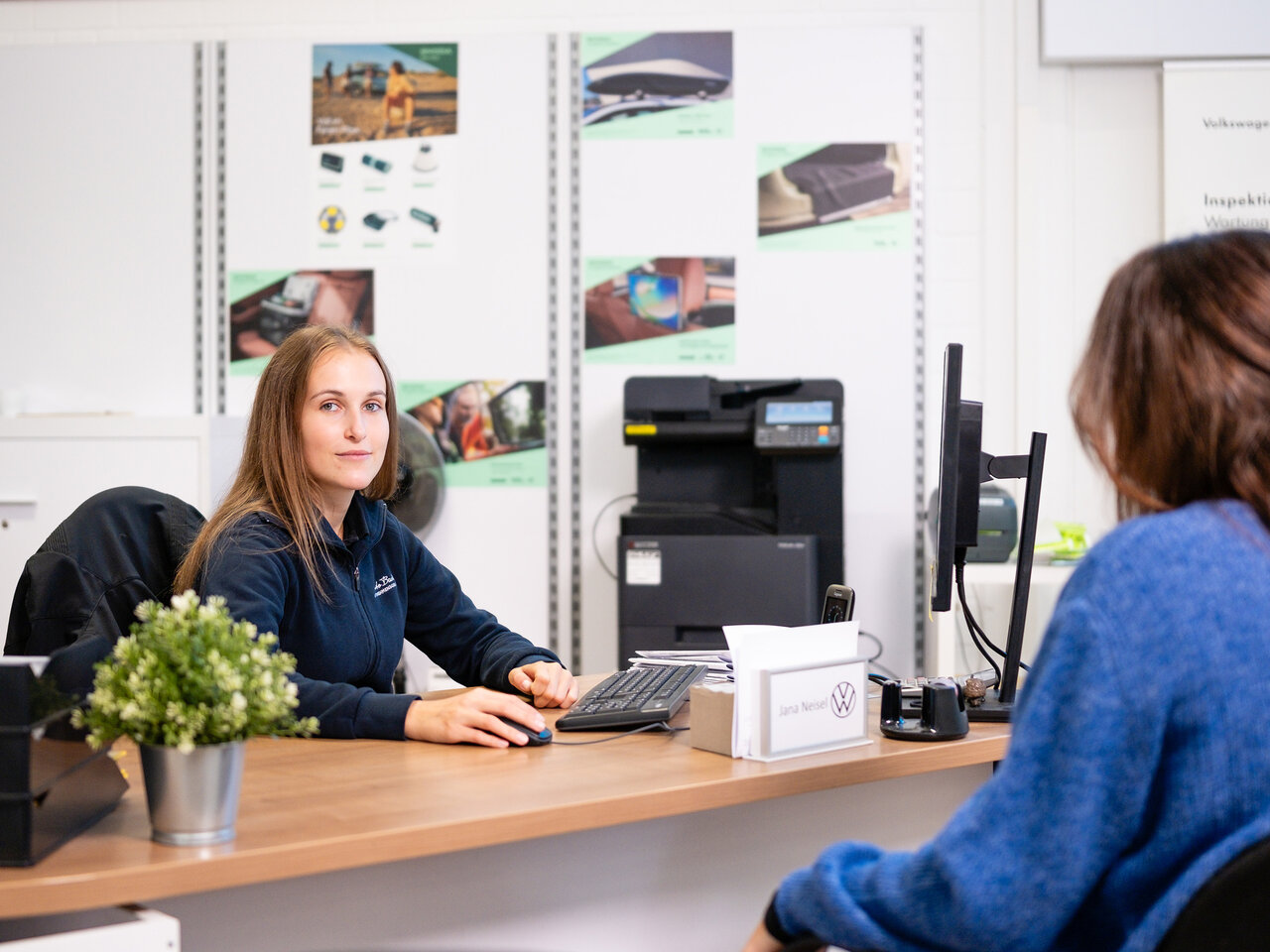 Mitarbeiterin im Auto Bach Servicebereich führt ein Beratungsgespräch mit Kundin am Schreibtisch eines Volkswagen Autohauses