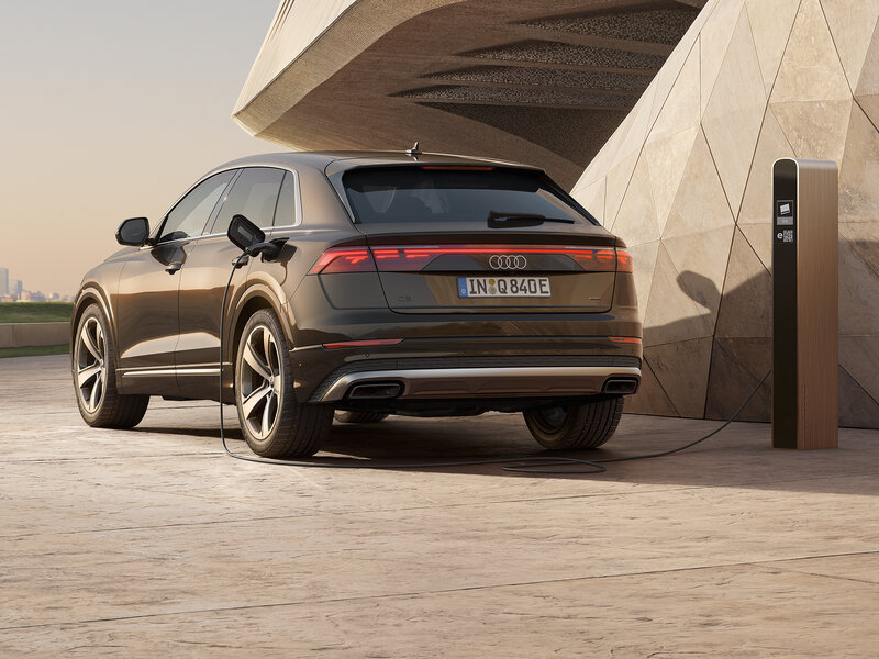 Audi Q8 e-hybrid von hinten beim Laden an moderner Wallbox mit LED-Rückleuchten und eleganter Linienführung