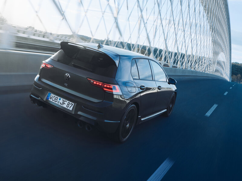 Heckansicht eines Volkswagen Golf R bei Fahrt auf einer Straße neben einer modernen Architektur.