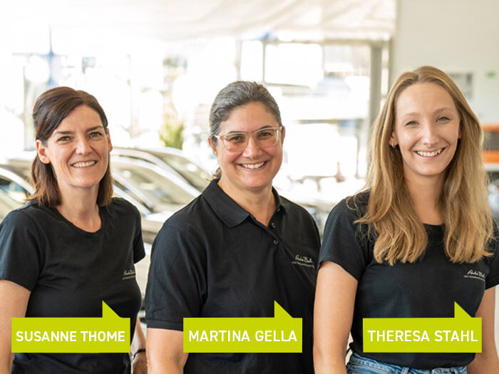 Drei Mitarbeitende der Auto Bach Gruppe stehen lächelnd nebeneinander und sind verantwortlich für die Betreuung der Auszubildenden.