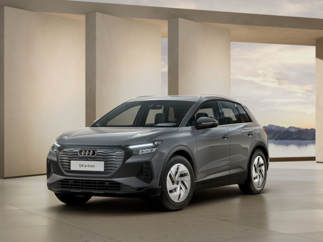 Grauer Audi Q4 e-tron steht in moderner Innenarchitektur mit hellem Boden und Blick auf eine Berglandschaft
