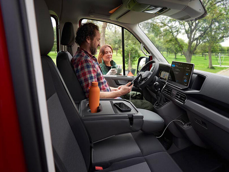 Blick in den Innenraum des Volkswagen Crafter mit Fahrer- und Beifahrersitz, Multifunktionslenkrad, digitalem Display und ergonomischem Arbeitsplatz.