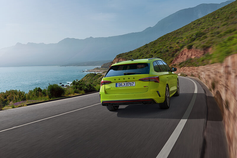 Škoda Octavia RS Combi in Mamba-Grün fährt auf einer kurvenreichen Küstenstraße mit Blick auf das Meer bei sonnigem Wetter
