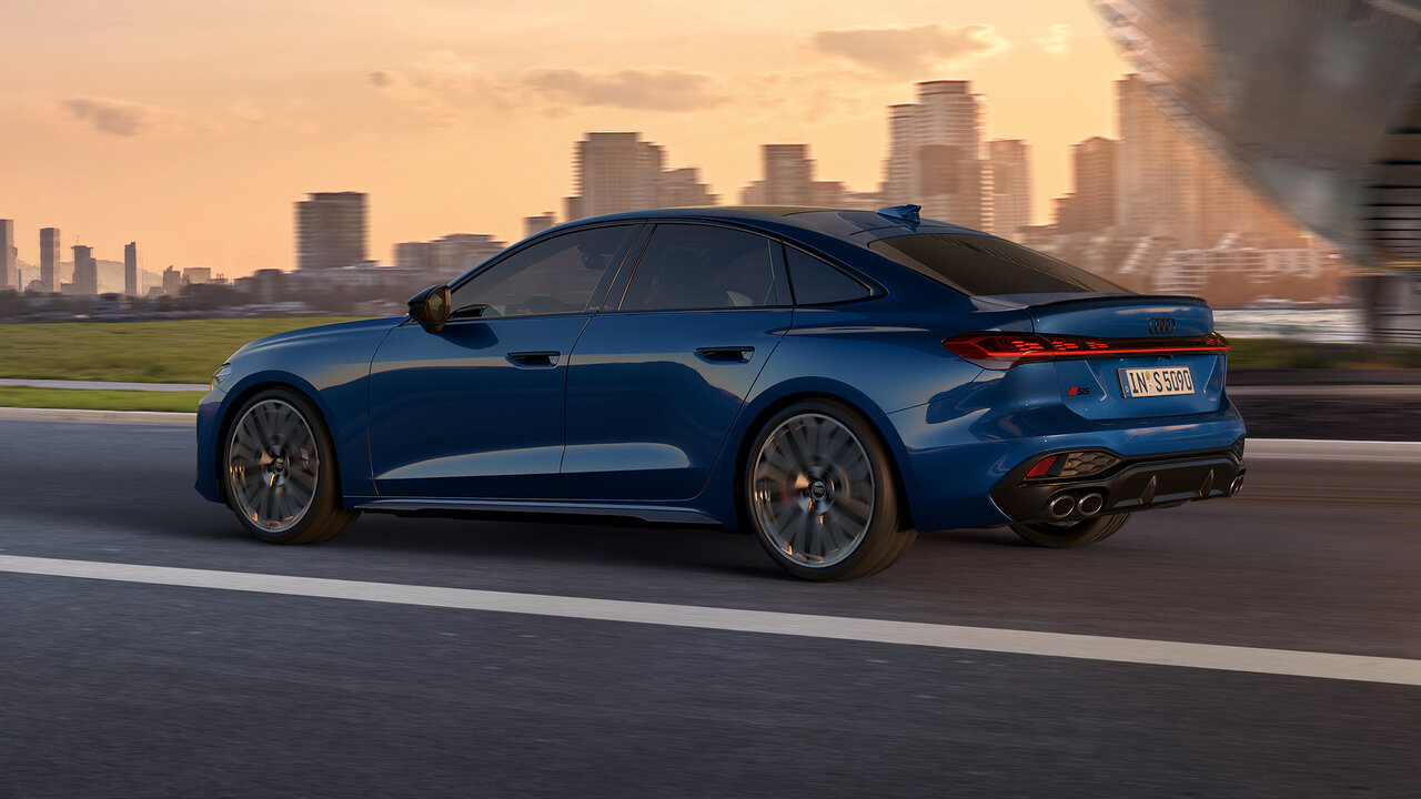 Blauer Audi S5 Limousine fährt bei Sonnenuntergang auf urbaner Straße, dynamische Seitenansicht mit Skyline im Hintergrund