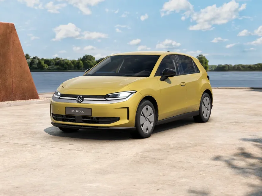 Volkswagen ID. Polo Life in Gelb steht in Dreiviertelansicht auf einer Betonfläche am Wasser unter blauem Himmel mit Wolken
