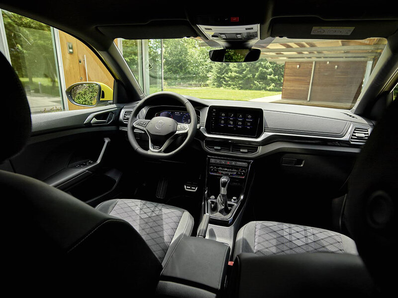 Innenansicht eines Volkswagen T-Cross mit Lenkrad, digitalem Kombiinstrument und zentralem Touchdisplay aus der Fahrerperspektive.