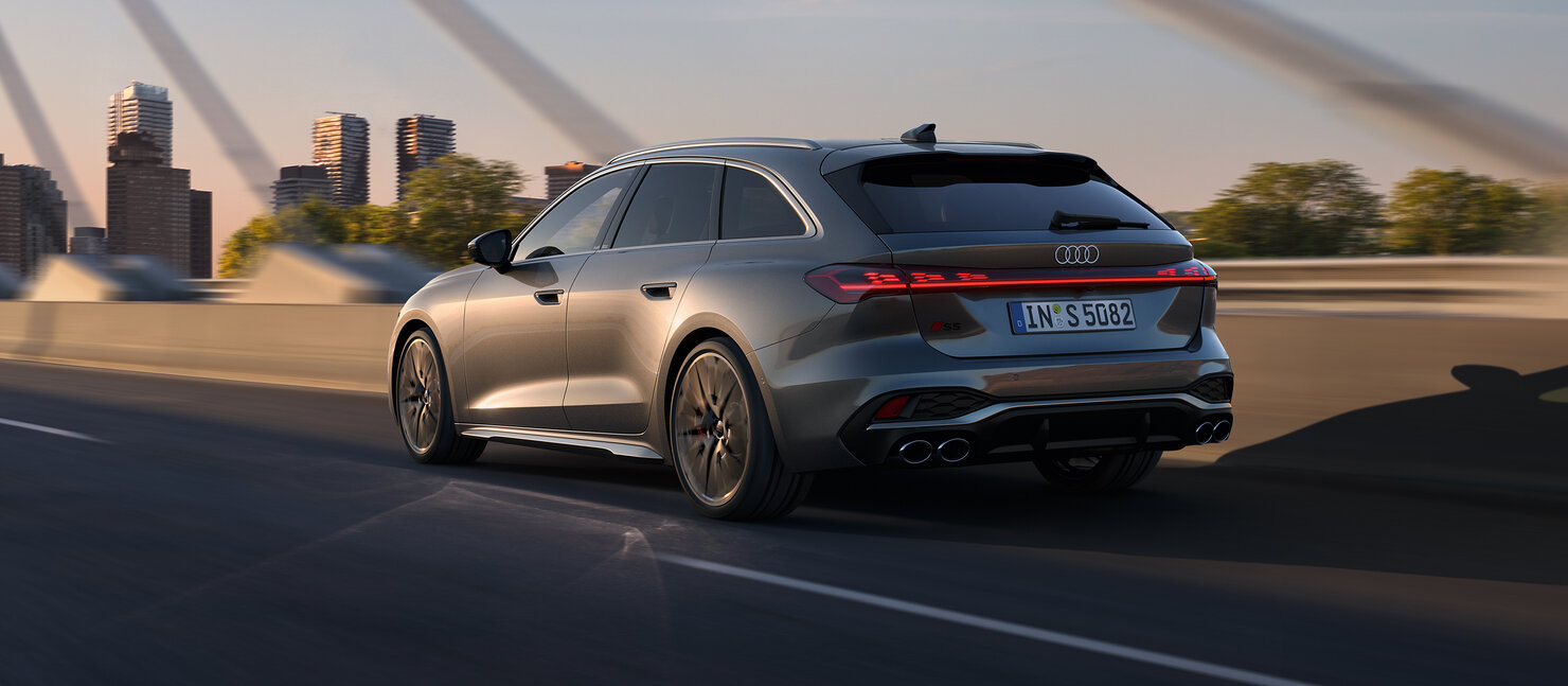 Audi S5 Avant in Fahrt über eine Stadtbrücke, gezeigt aus der Heckperspektive mit markanten Rückleuchten