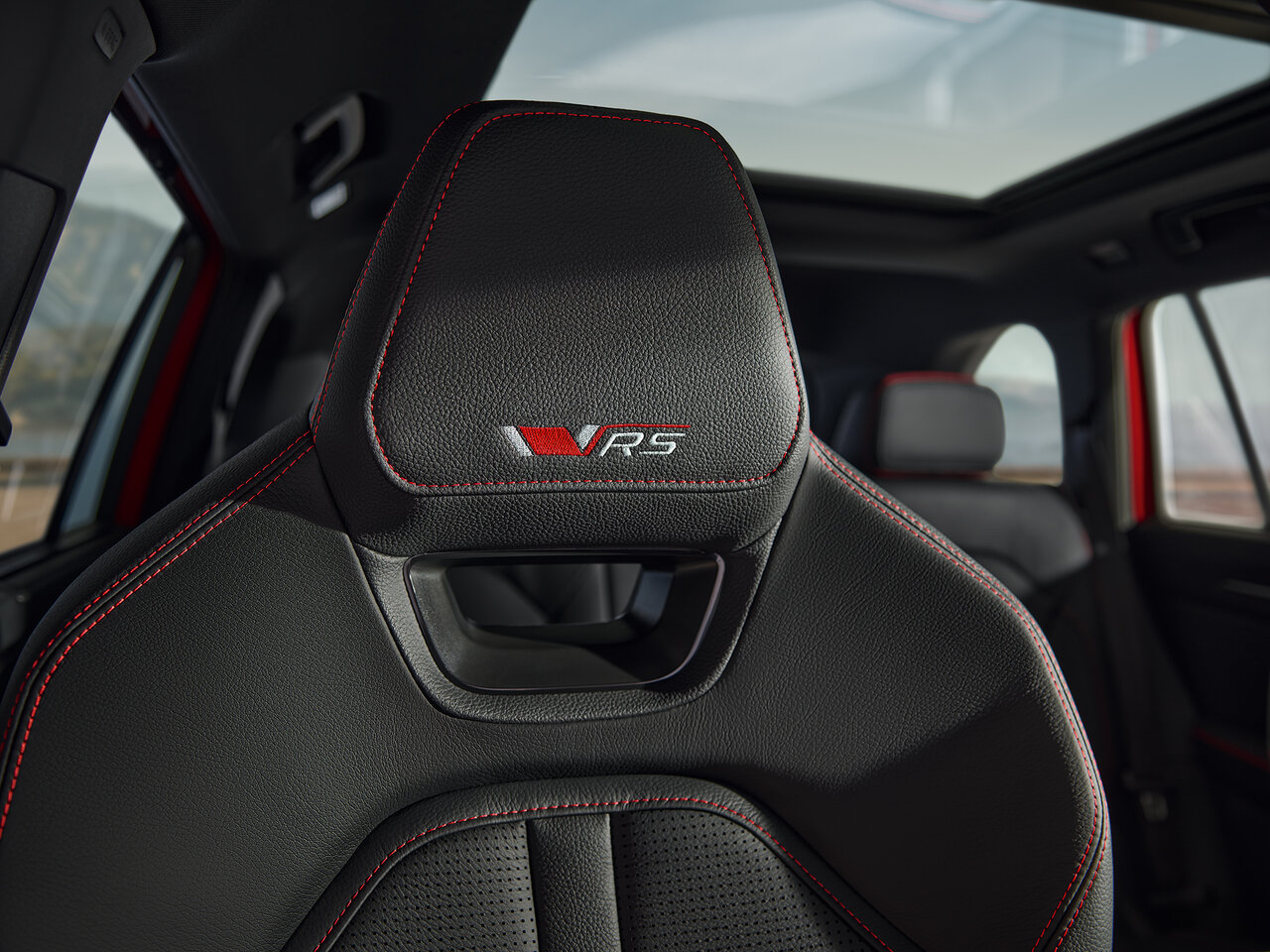 Sportsitz des Škoda Kodiaq RS mit roter Ziernaht und RS-Logo unter dem Panoramadach.
