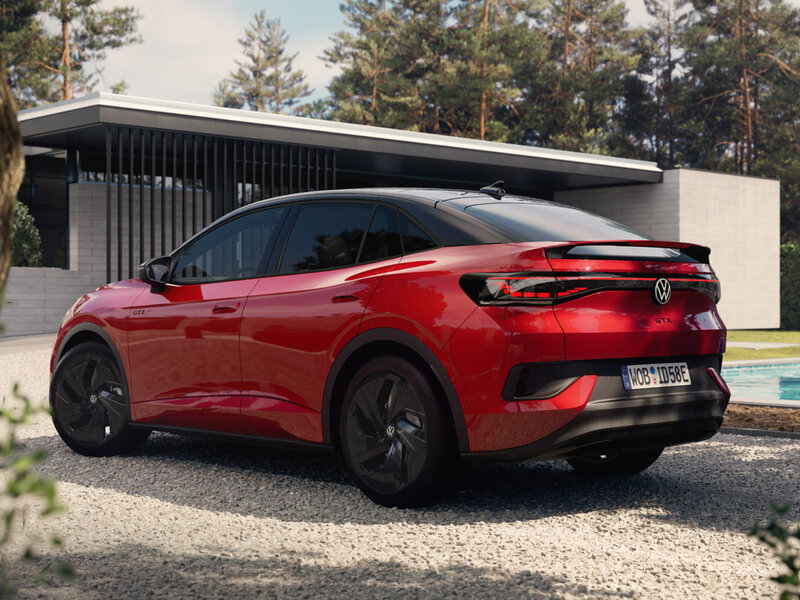 Roter VW ID.5 GTX von schräg hinten vor moderner Architektur; aerodynamisches Coupé-SUV-Design mit breiter Heckpartie.