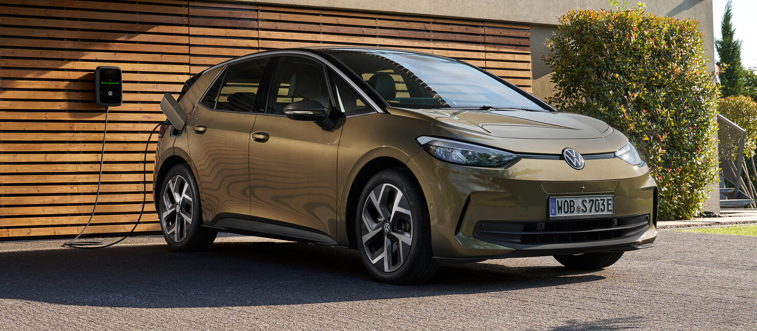 Goldfarbener Volkswagen ID.3 wird an einer Wallbox vor einem modernen Haus elektrisch geladen