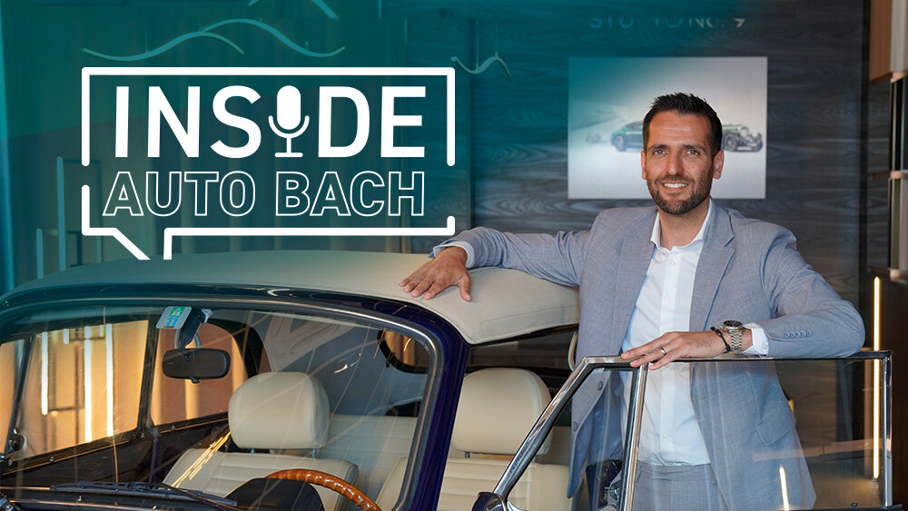 Sebastian Bach steht neben einem VW Käfer Cabrio im Showroom vor dem Schriftzug „Inside Auto Bach“