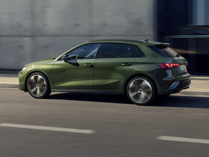 Grüner Audi A3 Sportback in dynamischer Fahrt von schräg hinten, sportlich-progressives Design in urbanem Umfeld