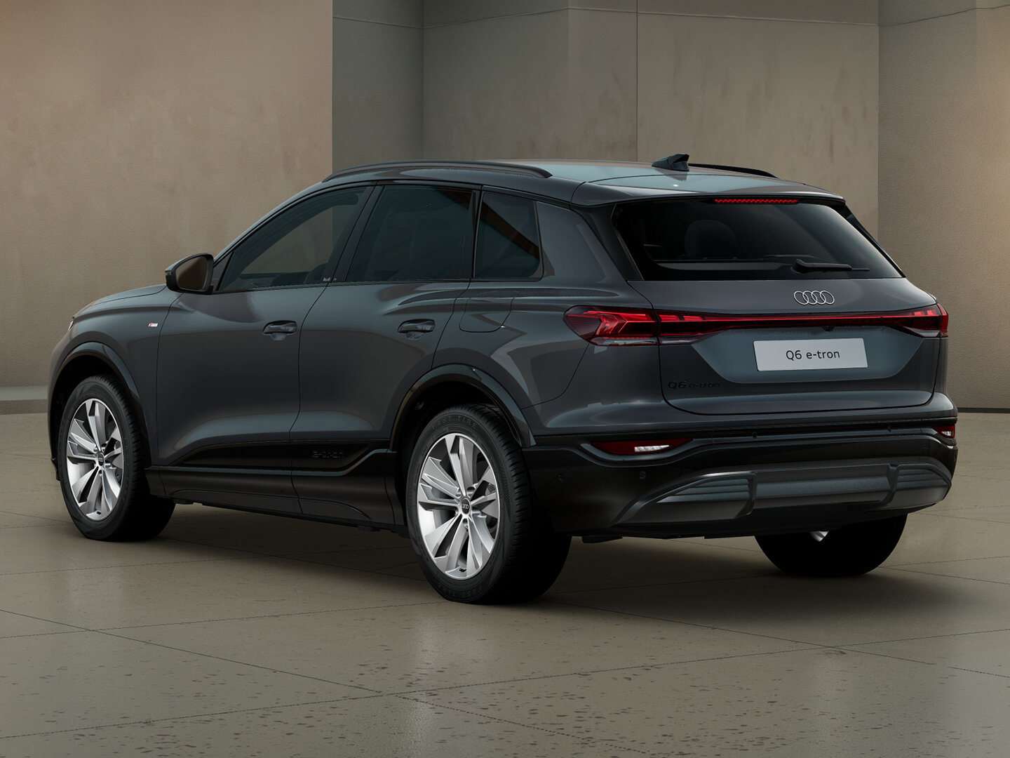 Audi Q6 e-tron in Heckansicht schräg von hinten vor moderner Architektur mit durchgehendem LED-Leuchtenband und markanter SUV-Silhouette