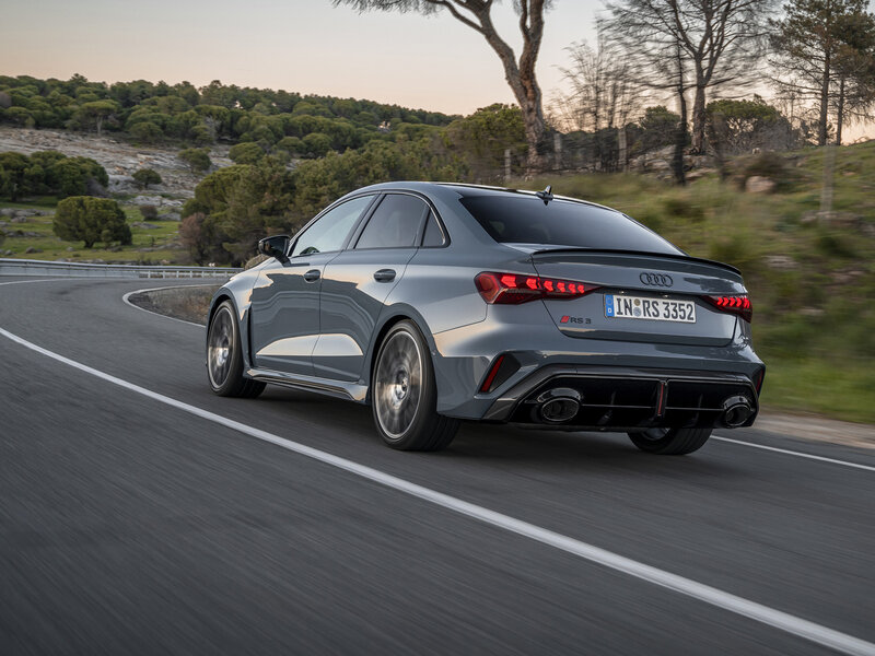 Heckansicht der Audi RS 3 Limousine in Fahrszene mit breitem Stand, Diffusor und charakteristischer Performance-Abgasanlage