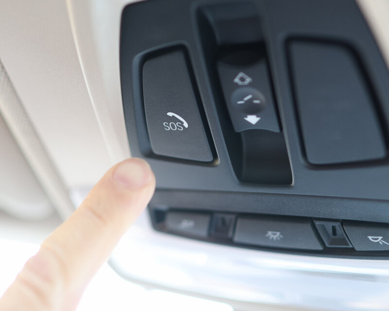Nahaufnahme eines Fingers, der im Fahrzeug den SOS-Notrufknopf im Dachbedienfeld betätigt