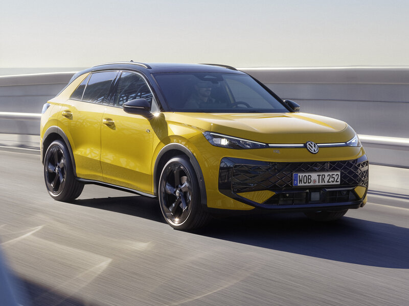 Ein gelber Volkswagen T-Roc fährt auf einer mehrspurigen Straße vor neutralem Hintergrund.