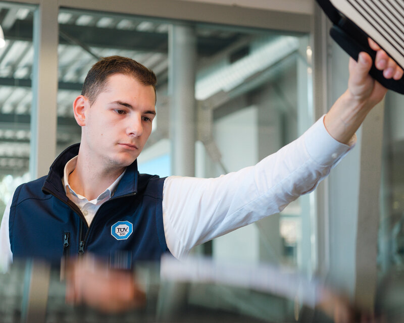 TÜV-Prüfer prüft Fahrzeug auf Lackschäden.