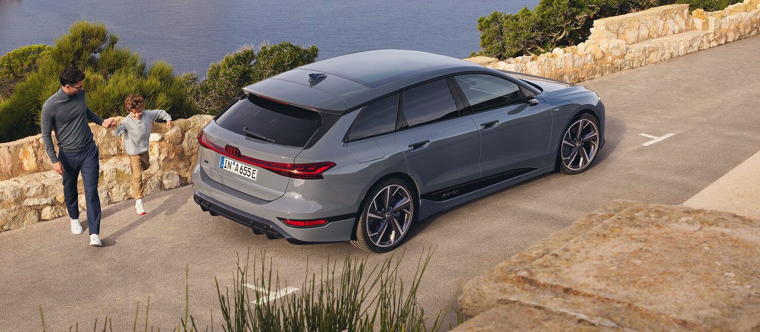 Audi A6 Avant e-tron aus erhöhter Heckperspektive auf Küstenstraße, dynamische Linienführung und aerodynamische Silhouette