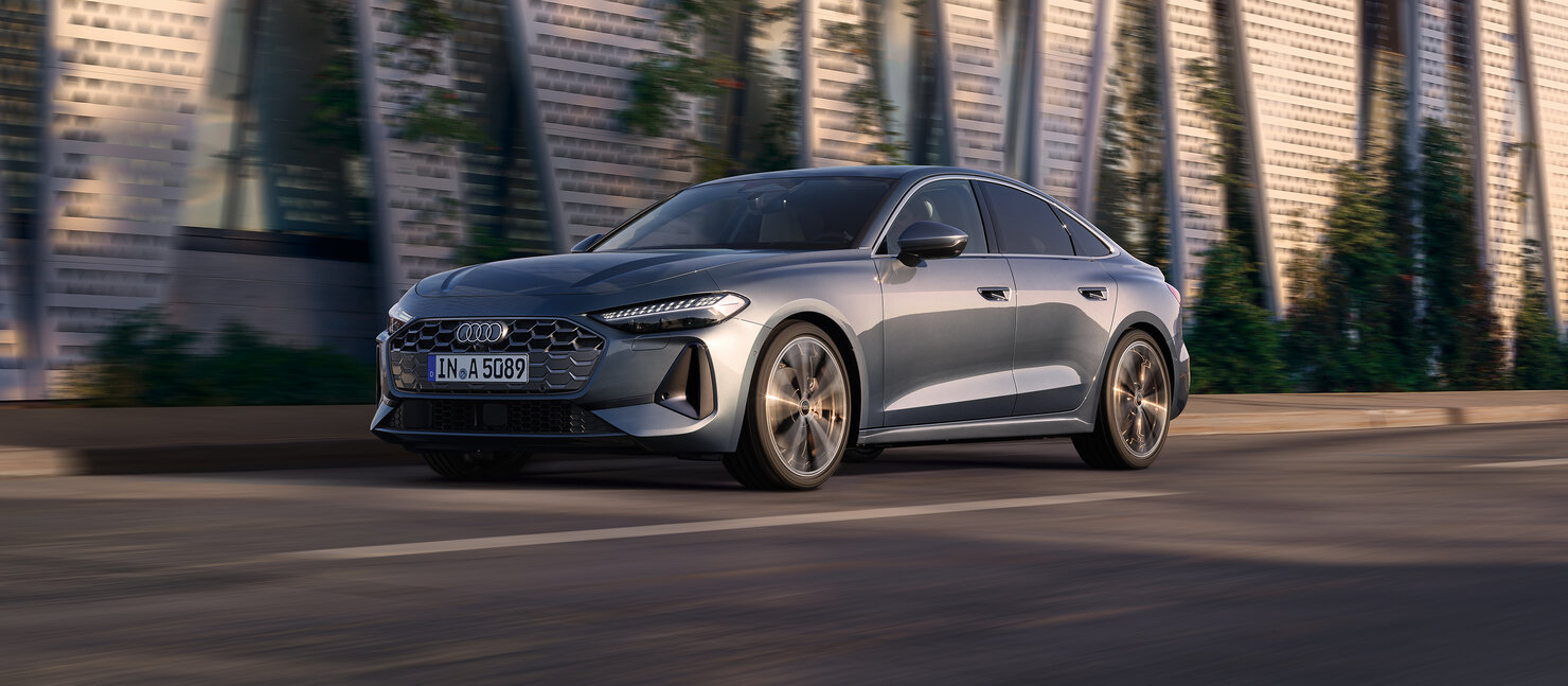 Audi A5 Limousine in Seitenansicht während der Fahrt, urbanes Umfeld mit moderner Fassadenarchitektur