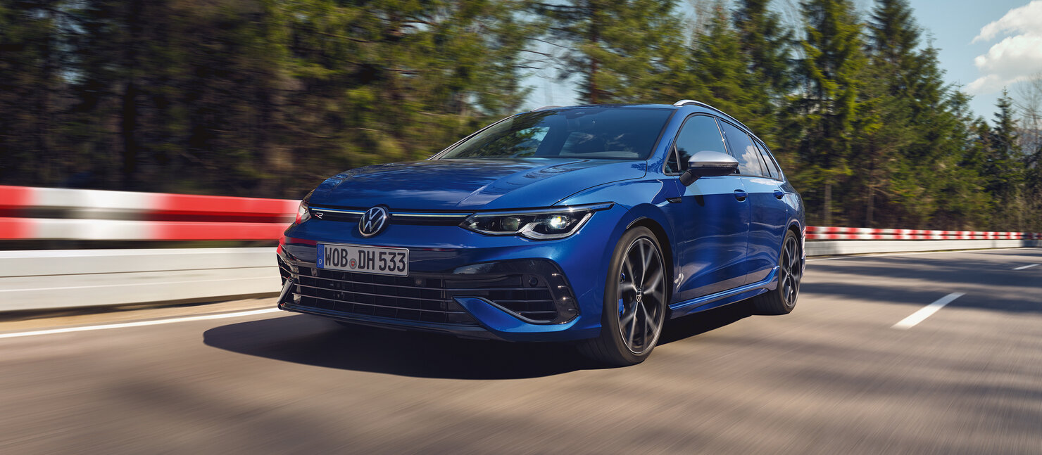 Blauer Volkswagen Golf Variant R fährt dynamisch auf kurviger Landstraße, sportliches Design in Bewegung