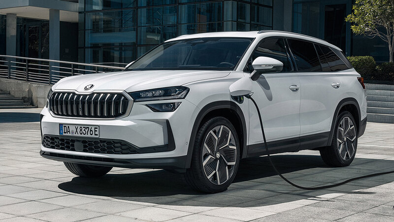 Škoda Kodiaq iV in Weiß steht an einer Ladestation vor moderner Architektur bei Tageslicht.