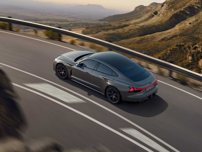 Audi RS e-tron GT fährt dynamisch auf Bergstraße, Heckansicht mit Coupélinie und LED-Leuchtenband