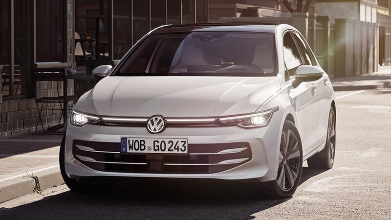 Weißer Volkswagen Golf steht auf einer sonnigen Stadtstraße nahe moderner Gebäude