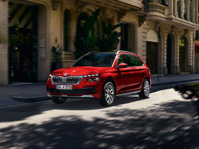 Škoda Kamiq in Rot steht auf einer schattigen Stadtstraße vor historischen Gebäuden.