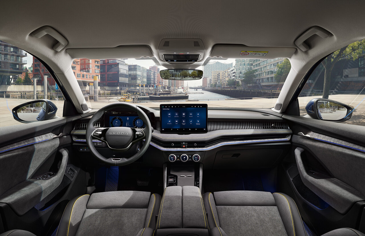 Innenraum des Škoda Superb Combi mit grauer Polsterung, großem Zentraldisplay und Blick auf eine moderne Stadtstraße