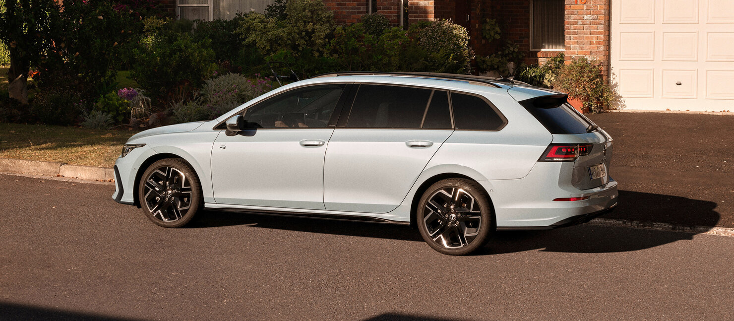 Volkswagen Golf Variant in heller Lackierung von der Seite, geparkt in ruhiger Wohnstraße vor Einfamilienhaus