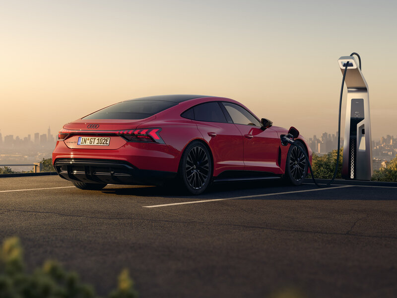 Audi e-tron GT quattro lädt an Schnellladesäule mit gestreckter Dachlinie und breiter Heckpartie