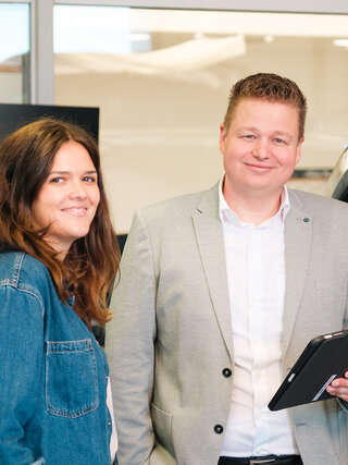 Zwei Personen stehen in der Škoda Werkstatt von Auto Bach in Diez neben einem grauen Fahrzeug mit Tablet auf der Hebebühne