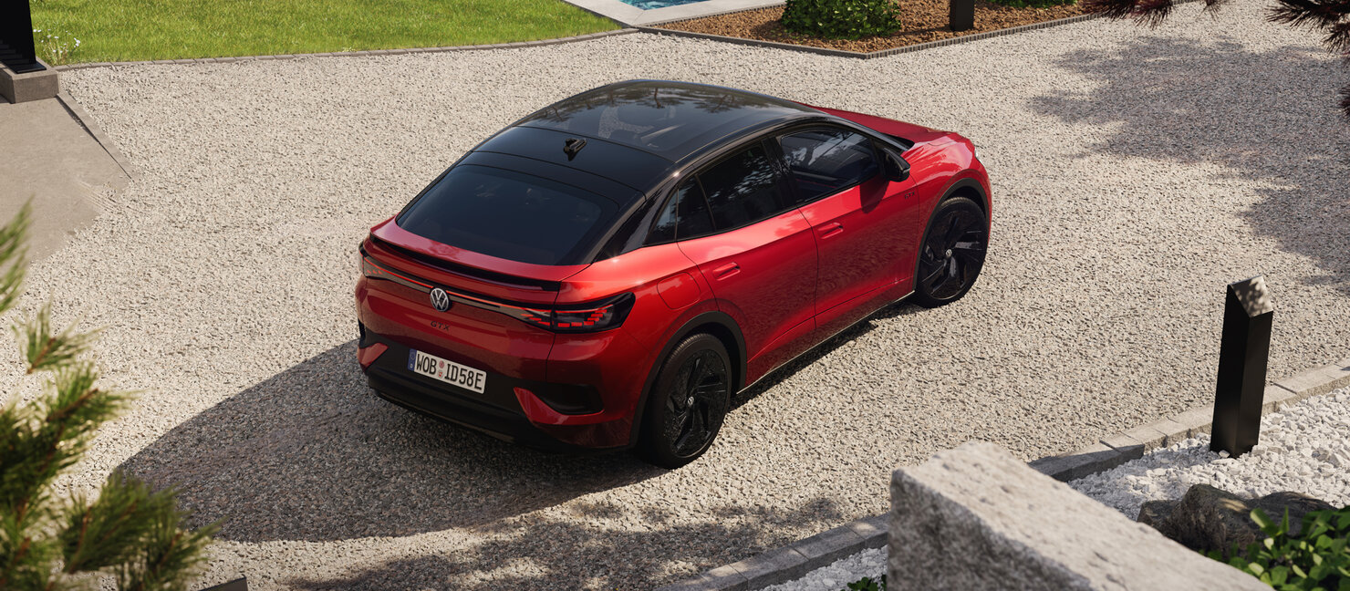Roter Volkswagen ID.5 GTX steht aus erhöhter Perspektive auf hellem Kieshof vor moderner Architektur