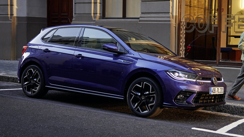 Volkswagen Polo in Violett parkt am Straßenrand vor einem Café in urbaner Umgebung