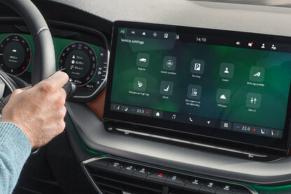 Fahrerbedienung im Innenraum eines Škoda-Fahrzeugs mit digitalem Cockpit und großem Zentraldisplay für Fahrzeugeinstellungen