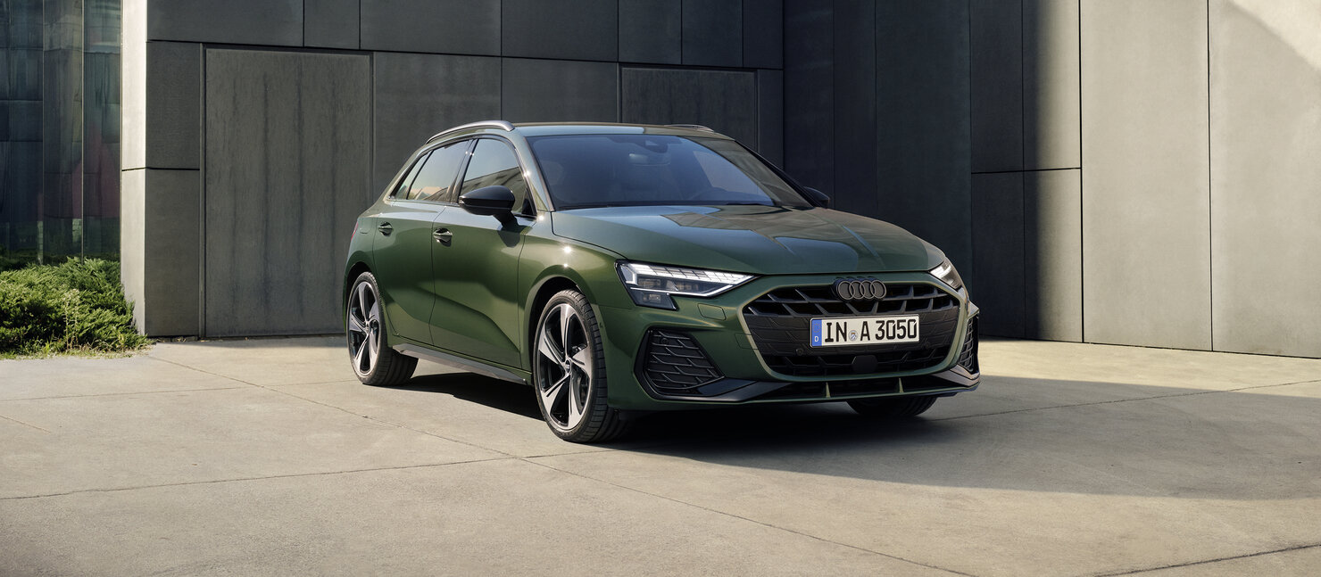 Audi A3 Sportback in Grün, schräg von vorn vor modernem Gebäude geparkt, mit klarer Linienführung und markantem Design