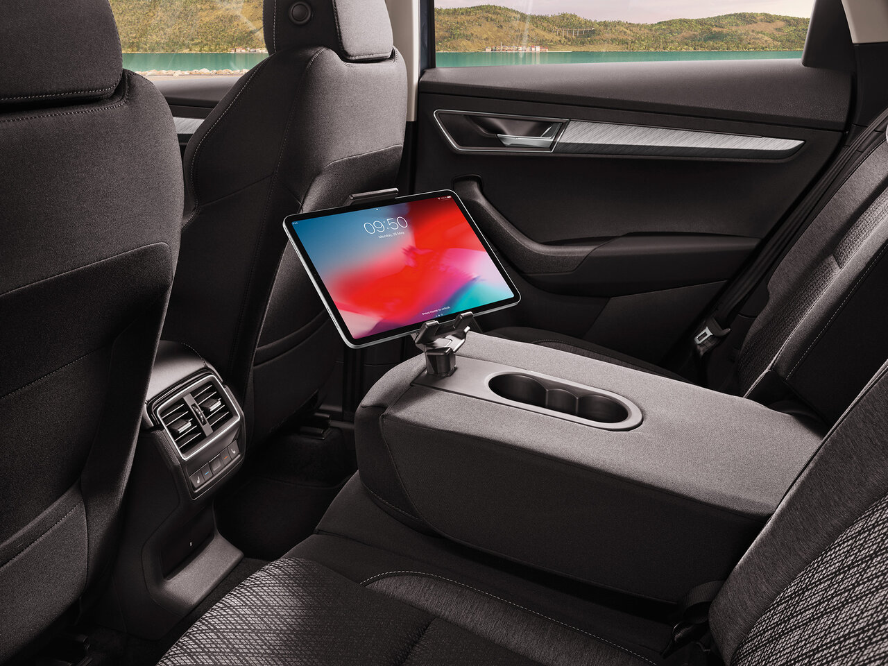 Rücksitzbereich des Škoda Karoq mit ausgeklappter Mittelarmlehne und einem Tablet auf der Halterung hinter dem Vordersitz.