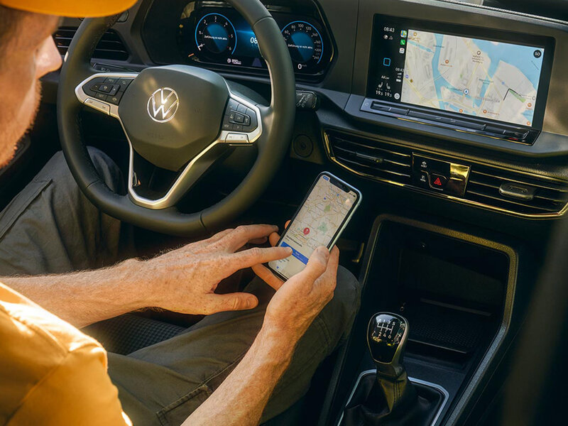 Blick in den Innenraum des Volkswagen Caddy California mit Multifunktionslenkrad, digitalem Kombiinstrument und zentralem Touchscreen mit Navigationsanzeige.