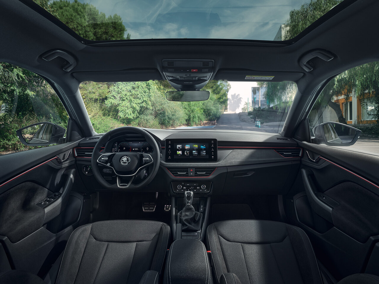 Cockpit des Škoda Scala Monte Carlo mit Panoramadach, roten Ziernähten und zentralem Display, gesehen aus der Rücksitzperspektive