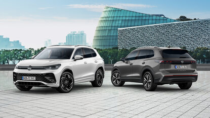 Zwei Volkswagen Tiguan stehen nebeneinander auf gepflastertem Platz vor moderner Architektur in urbaner Umgebung