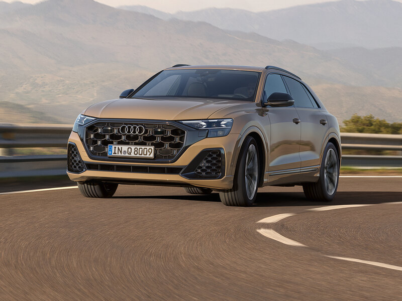 Audi Q8 in dynamischer Kurve mit sportlicher Coupé-Silhouette, markantem Singleframe-Grill und breitem Stand