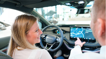 Zwei Personen sitzen im Innenraum eines neuen Škoda und bedienen das Infotainmentsystem mit Navigationsanzeige.