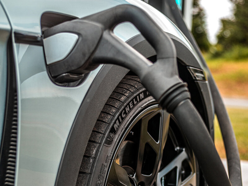 Detailaufnahme eines Porsche Taycan mit angeschlossenem Ladekabel während des Ladevorgangs.