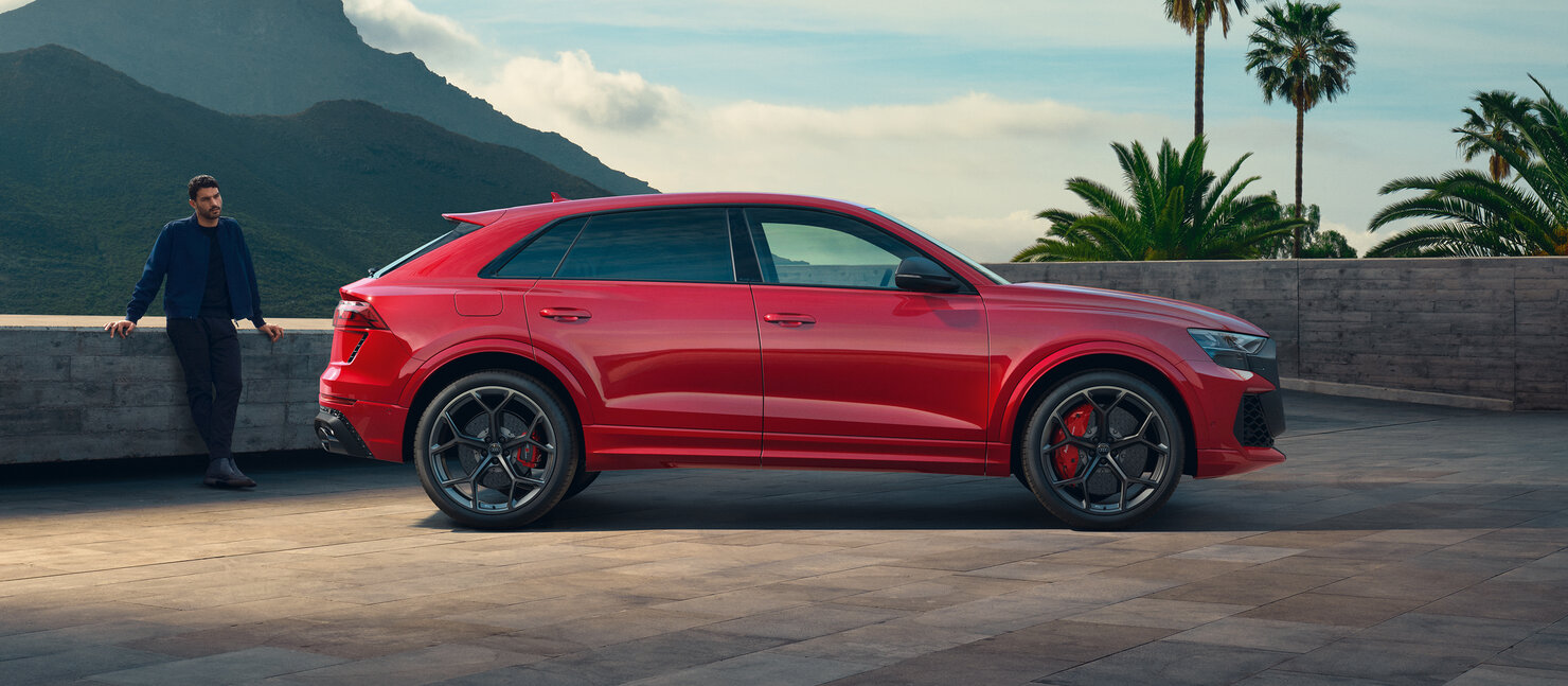 Audi RS Q8 in Seitenansicht vor moderner Architektur, kraftvolle SUV-Coupé-Silhouette mit breiter Spur und RS-Details
