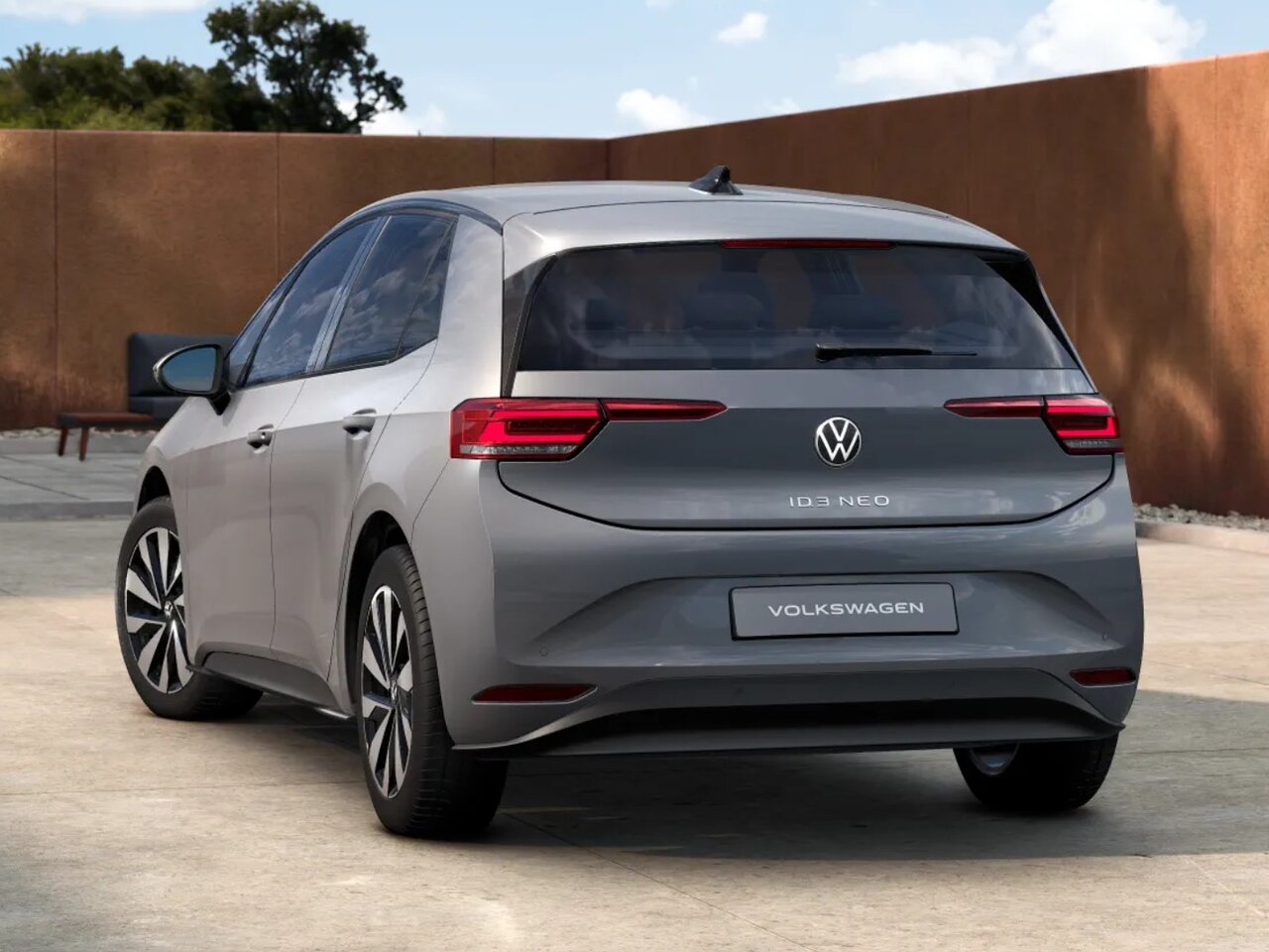 Volkswagen ID.3 Neo in Grau aus Heckansicht vor moderner Architektur bei sonnigem Himmel